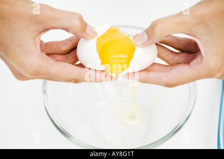 Fissuration femme oeuf dans bol, cropped view of hands, high angle view Banque D'Images
