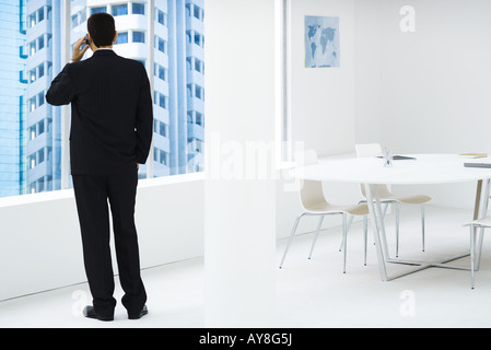 Woman, looking out window, using cell phone Banque D'Images