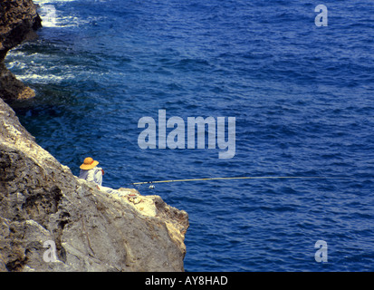 Pêcheur Okinawan assis sur les falaises du cap Zampa Banque D'Images