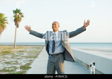 Plage man with arms raised, smiling Banque D'Images