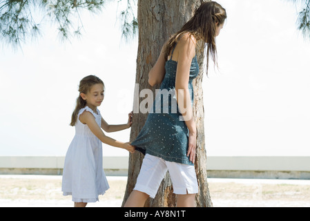 Deux soeurs debout à côté d'un tronc d'arbre, la tenue à l'autre par la chemise avec les yeux fermé Banque D'Images