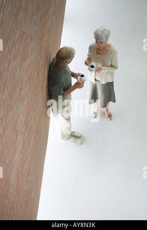 Couple debout face à face, les deux tenant des tasses à café, high angle view Banque D'Images