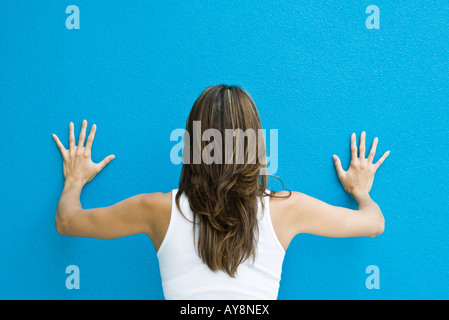 Femme debout avec les mains contre le mur bleu, vue arrière Banque D'Images