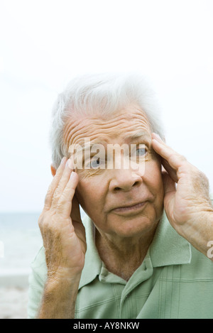 Senior man with hands on temples, à l'écart, close-up Banque D'Images