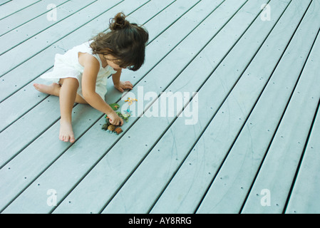 Petite fille assise sur le pont, à jouer avec des jouets en plastique, high angle view Banque D'Images