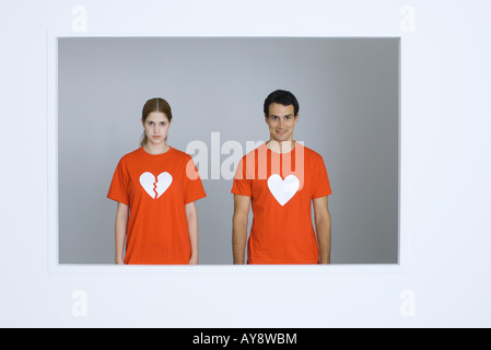 Jeune couple portant des tee-shirts avec des symboles, woman's coeur brisé Banque D'Images