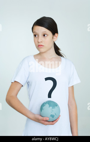 Girl wearing tee-shirt imprimé avec point d'interrogation, holding globe, looking away Banque D'Images