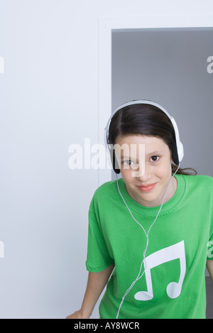 Preteen girl wearing tee-shirt imprimé avec des notes de musique, l'écoute au casque, smiling Banque D'Images