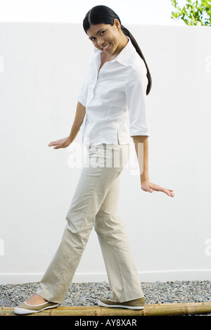 Femme debout sur les poteaux de bambou, smiling at camera, pleine longueur Banque D'Images