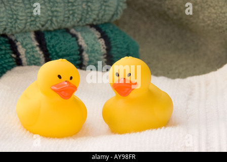 Deux canards en caoutchouc s'asseoir sur l'assainissement des serviettes de bain moelleuses en attente d'un temps d'amusement dans la baignoire. Banque D'Images