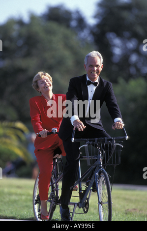 Caucasian couple cycliste sur vélo tandem portant la tenue de ville Banque D'Images