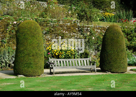 Haddon Hall banc de parc en bois entre deux arbustes conifères dans les jardins de la demeure de Lord Edward Manners Bakewell Derbyshire Banque D'Images