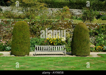 Haddon Hall banc de parc en bois entre deux arbustes conifères dans les jardins de la demeure de Lord Edward Manners Bakewell Derbyshire Banque D'Images