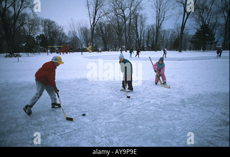 Certains enfants tomber une rondelle hokey sur tandis que d'autres profiter d'une piste de patinage Park de Kingston Ontario Canada Banque D'Images