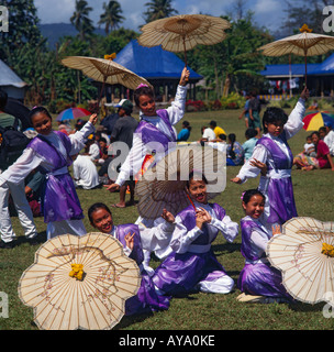 Six femmes fidjiennes chinois danseurs dans un groupe posés avec le joli soleil blanc brollies vêtus de longues robes de satin violet et blanc Banque D'Images