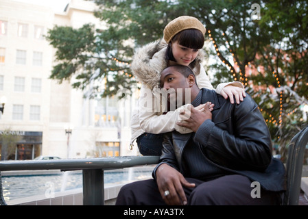 Jeune couple inter-raciale sur un banc de parc Banque D'Images