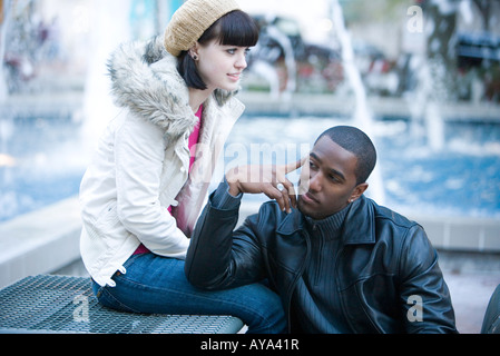 Close-up of a young contemplative couple inter-raciale sur un banc de parc Banque D'Images