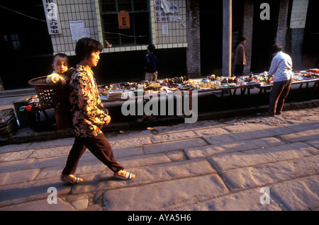 La province du Sichuan en Chine Shi Bao Zhai mère porte sa fille dans les rues de la ville, le long de la rivière Yangtze, au coucher du soleil Banque D'Images