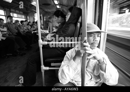 L'Indonésie Jakarta passagers assis par porte ouverte de trains de banlieue bondés à Kota Railway Station pendant l'heure de pointe du matin Banque D'Images