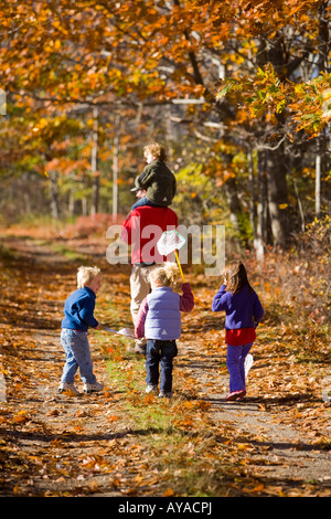 Un homme porte son fils(4 ans) sur ses épaules sur un sentier forestier à Biddeford, Maine. Trois enfants suivent. Banque D'Images