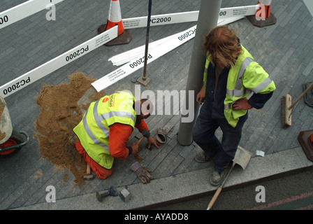 Londres à la semi bas antenne sur 2 deux ouvriers rétablissant le pavage autour de la base du lampadaire Banque D'Images