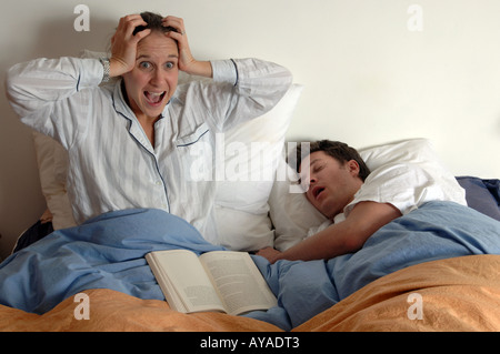 Femme avec les mains sur les oreilles en hurlant la frustration de partenaires qui ronflent Banque D'Images