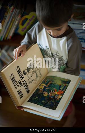 Garçon âgé de 6 ans lit livre de contes et comptines Banque D'Images