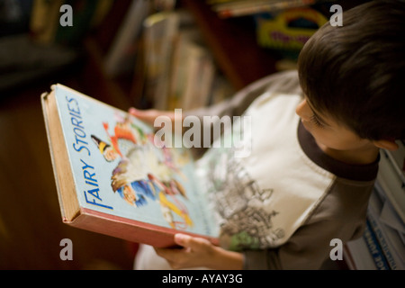 Garçon âgé de 6 ans lit livre de contes et comptines. Banque D'Images