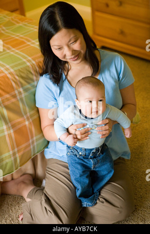 Portrait d'une mère asiatique assis sur le sol tenant un bébé garçon sur ses genoux Banque D'Images