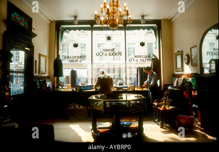 Des maîtres tailleurs travaillant dans la boutique soleil intérieur de l'exposition d'antiquités d'Henry Poole & Co, Bond Street, Mayfair, London Banque D'Images