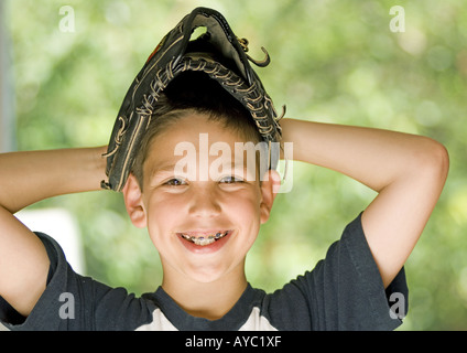 Smiling boy wearing baseball glove sur sa tête Banque D'Images