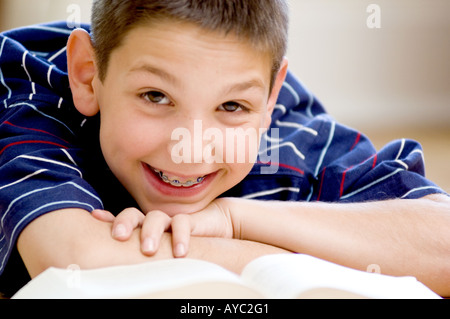 Smiling boy à bretelles jusqu'à lors de la lecture de livre Banque D'Images