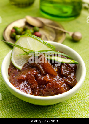 Un bol de chili et de lime chutney avec un fond vert table setting Banque D'Images