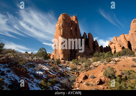 Les formations de nuages whispy sur des formations rocheuses avec neige de l'hiver au parc national Arches Banque D'Images