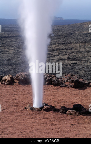 L'eau est versée dans un trou et quelques secondes plus tard l'eau éclate de nouveau dans l'air comme la vapeur sur le Parc National de Timanfaya, Banque D'Images