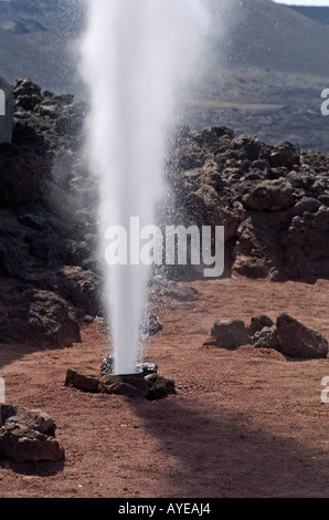 L'eau est versée dans un trou et quelques secondes plus tard l'eau éclate de nouveau dans l'air comme la vapeur sur le Parc National de Timanfaya, Banque D'Images