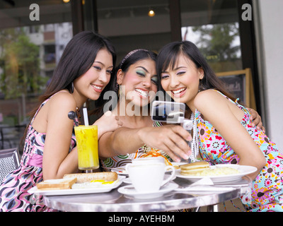 Trois femmes au jardin extérieur café, prise de photos Banque D'Images