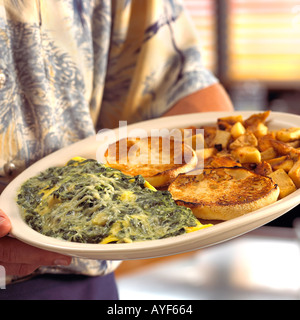Serveur Restaurant holding épinards et fromage omelette avec muffin anglais et les pommes de terre sur la plaque Banque D'Images