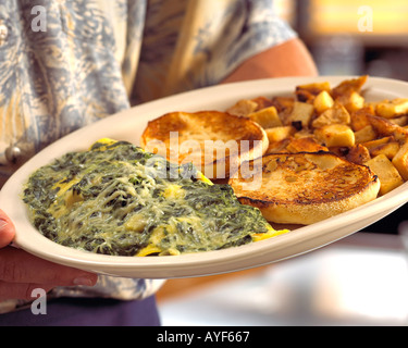 Serveur Restaurant holding épinards et fromage omelette avec muffin anglais et les pommes de terre sur la plaque Banque D'Images