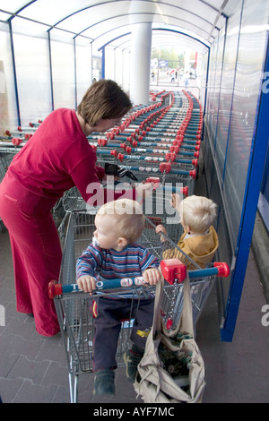 Maman polonaise plaçant coin dans la fente pour déverrouiller votre panier au supermarché Tesco. Le Centre de la Pologne Lodz Banque D'Images
