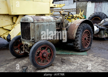 Old rusty tracteur avec pneus Dunlop assis en face d'une moissonneuse-batteuse agricole ferme vintage Banque D'Images