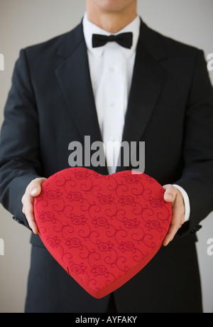 Man in tuxedo holding heart shaped box