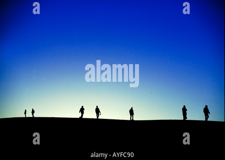 Tourisme touristes sur les dunes de sable en silhouette contre le soleil du désert du Sahara, l'Erg Chebbi Maroc Banque D'Images