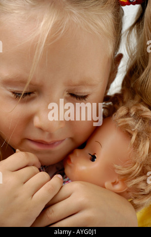 Crying little girl holding sa poupée Banque D'Images