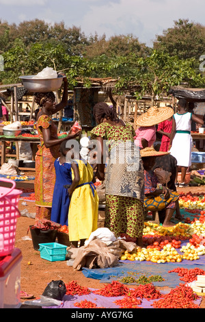 Mère de deux filles d'acheter des tomates de trader en ville de l'Afrique de l'Ouest du Ghana, du marché Banque D'Images