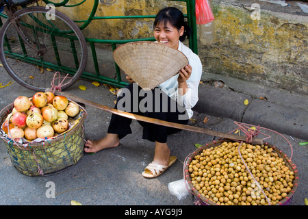 Femme portant un chapeau de riz vietnamien traditionnel vend des produits frais et de grenadiers des Longanes Hanoi Vietnam Banque D'Images