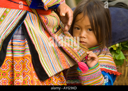 Jeune fille Flower Hmong se cache dans sa mère s Jupe Bac Ha marché près de Sapa Vietnam Banque D'Images