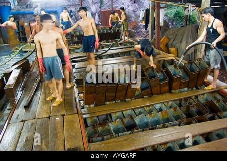 Les hommes qui travaillent dans une fabrique de glace produire de la glace pour les bateaux de pêche qui entrent dans le port de l'île Cat Ba Baie de Halong Vietnam Banque D'Images