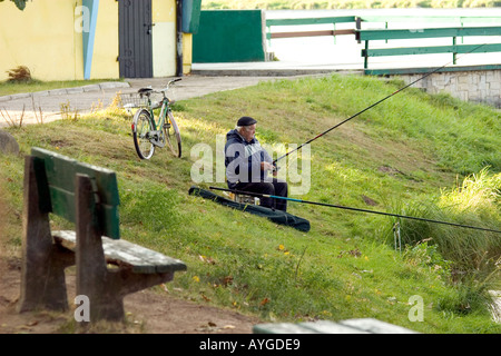 L'homme avec son vélo la pêche dans le lagon à Tatar Zalew waterfront park. Warszawa Pologne Banque D'Images