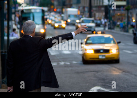 Un homme d'affaires en tailleur avec son bras héler un taxi Manhattan New York NY USA Banque D'Images